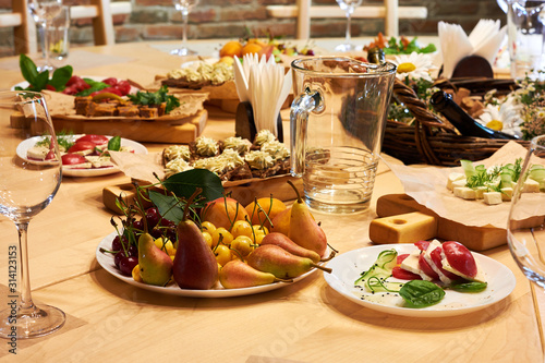 Served wooden table with a set of variety snacks, different vegetable salads, salad, pickle carrot, kavarma, rye bread sandwiches with soft cheese cream, fruits,
