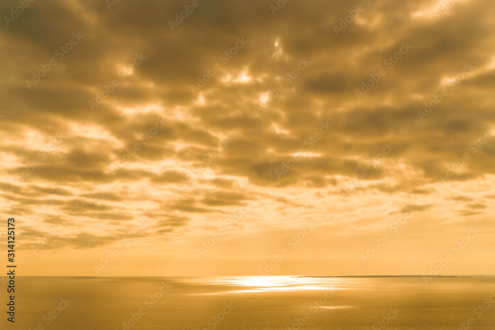 Yellow Sunset on the sea with overcast sky.  Orange pastel tone