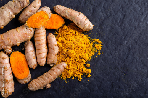 Food and drink, diet nutrition, health care concept. Raw organic orange turmeric root and powder, curcuma longa on a grunge cooking table. Indian oriental low cholesterol spices photo