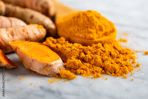 Food and drink, diet nutrition, health care concept. Raw organic orange turmeric root and powder, curcuma longa on a grunge cooking table. Indian oriental low cholesterol spices