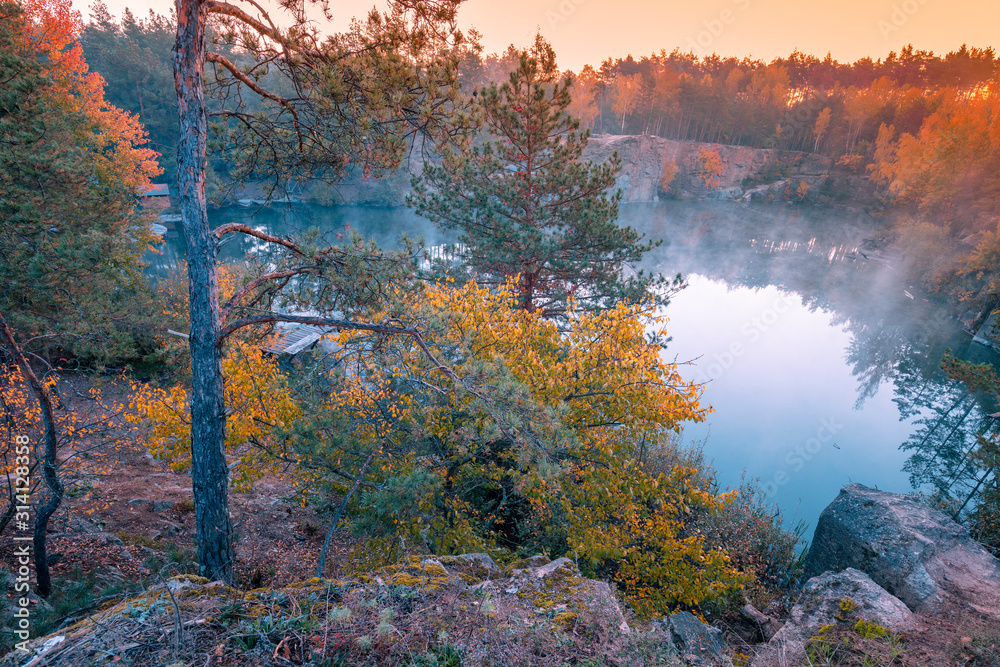 Early foggy morning. Sunrise over a lake with a rocky shore. Nature landscape in autumn