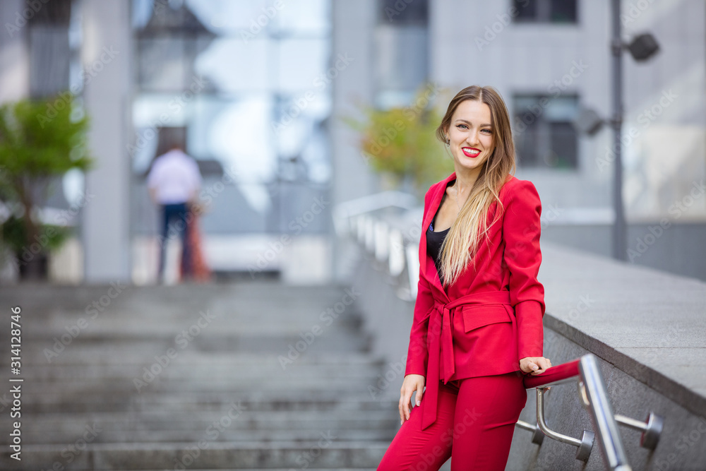 Attractive young woman standing on stairs in business district and smiling Attractive young woman standing on stairs in business district and smiling
