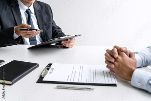 Senior committee manager reading a resume during a job interview, Employer interviewing to ask young male job seeker for recruitment talking in office