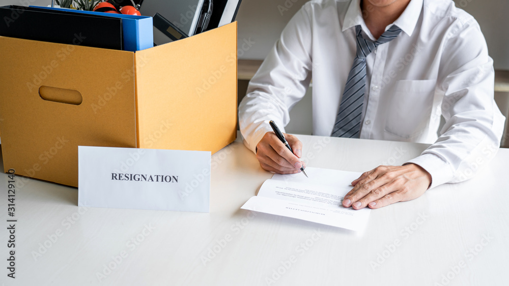 Images of packing up all his personal belongings and files into a brown cardboard box, Businessman has stress to resignation and signing cancellation contract letter in office, resign concept Images of packing up all his personal belongings and files into a brown cardboard box, Businessman has stress to resignation and signing cancellation contract letter in office, resign concept