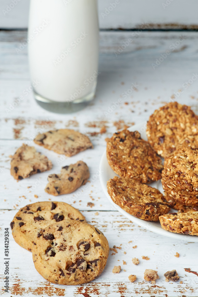 White plate with healthy snack granola whole grain cookies and glass cup of milk on wooden surface. Healthy food and lifestyle concept White plate with healthy snack granola whole grain cookies and glass cup of milk on wooden surface. Healthy food and lifestyle concept