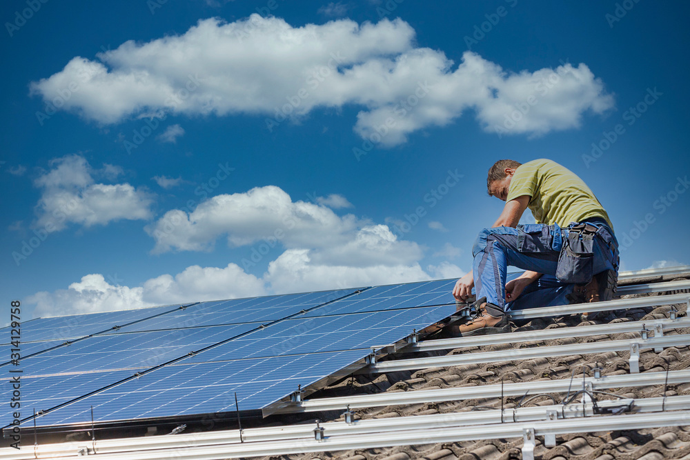 Installing solar photovoltaic panel system. Solar panel technician installing solar panels on roof. Alternative energy ecological concept. Installing solar photovoltaic panel system. Solar panel technician installing solar panels on roof. Alternative energy ecological concept.
