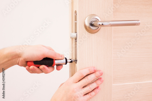 Handyman installing and repair the lock in front wooden interior door.