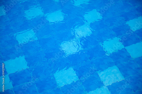 Water surface of a swimming pool, tiled with blue mosaic, giving a blurred impression