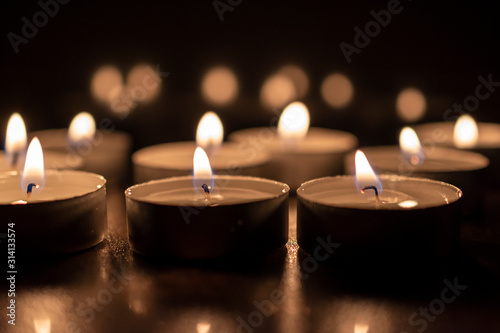 close up of burning candles on black table in the dark.