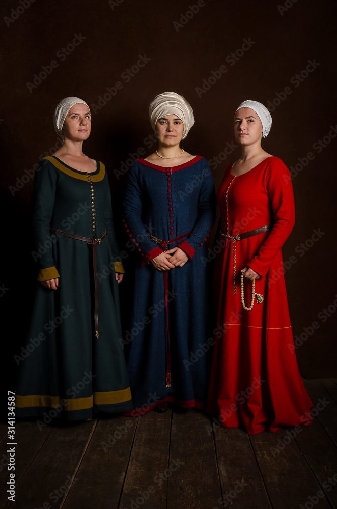 Three beautiful sophisticated actress girls in a medieval costume of the 14th century central Europe. Hobby - reconstruction of historical events.