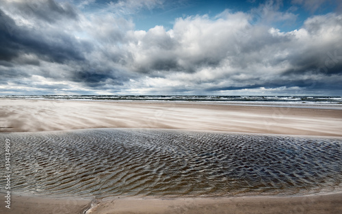 Storm clouds above the sea. Waves and water splashes. Warm evening sunlight. Baltic sea, Garciems, Latvia photo