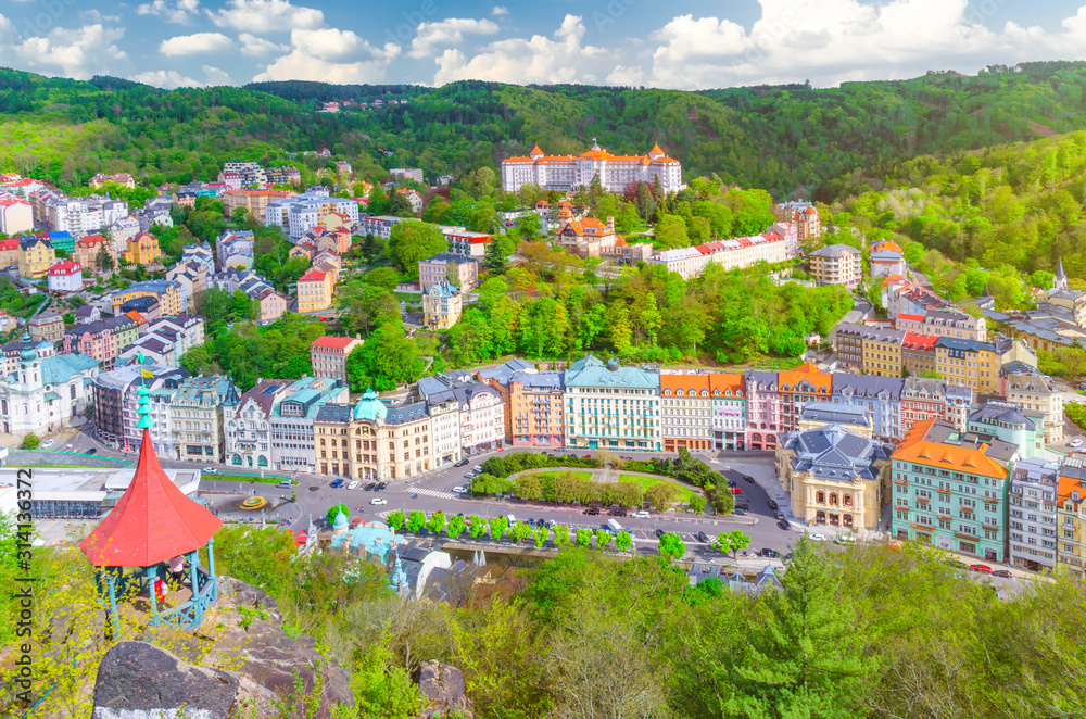 Karlovy Vary (Carlsbad) historical city centre top aerial view with colorful beautiful buildings, Slavkov Forest hills with green trees and Deer Jump Jeleni Skok Lookout, West Bohemia, Czech Republic