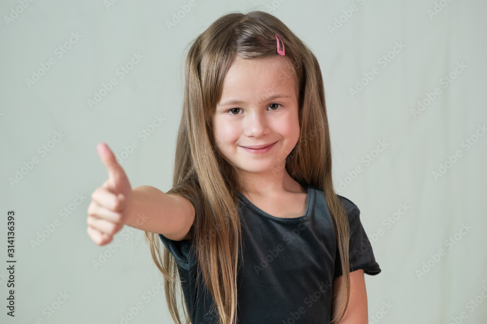 Close-up portrait of happy smiling little girl with long hair showing super sign with her thumbs up. Close-up portrait of happy smiling little girl with long hair showing super sign with her thumbs up.