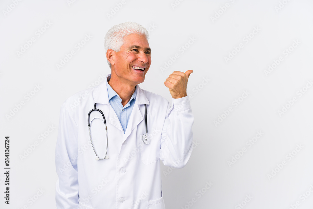 Mature caucasian doctor man points with thumb finger away, laughing and carefree. Mature caucasian doctor man points with thumb finger away, laughing and carefree.