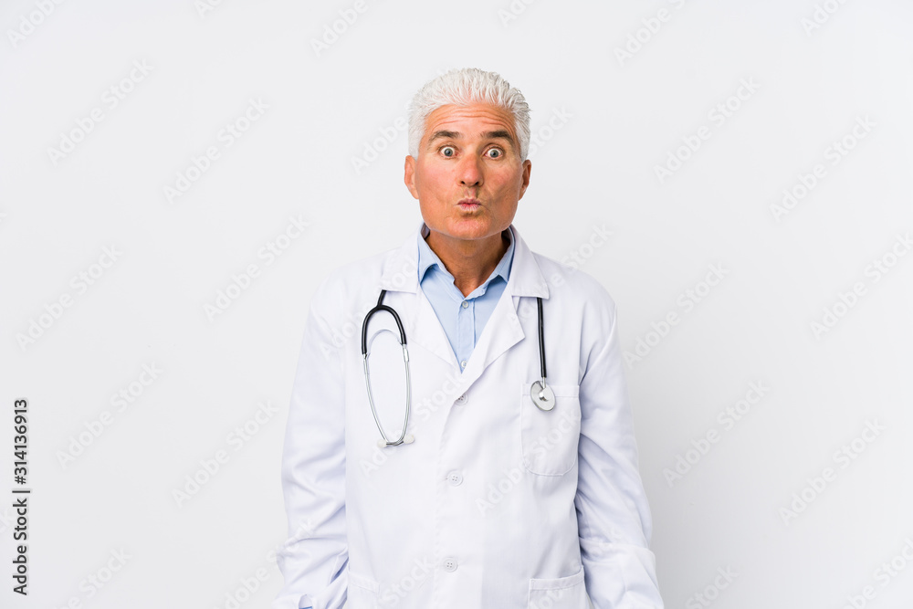 Mature caucasian doctor man shrugs shoulders and open eyes confused. Mature caucasian doctor man shrugs shoulders and open eyes confused.