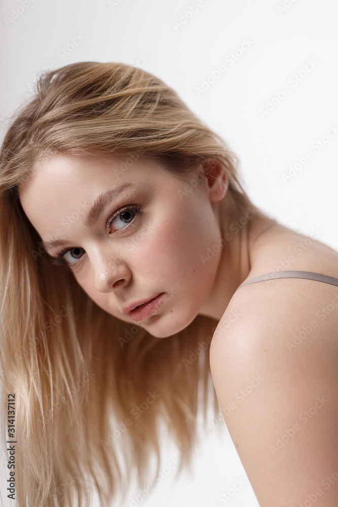 pretty blonde caucasian girl with naked shoulders and long hair looking at  camera. beauty portrait, close