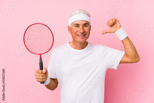 Middle aged man playing badminton isolated feels proud and self confident, example to follow. © Asier