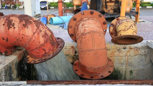 Water Splash flowing from rusted metal culvert drain pipe opening 