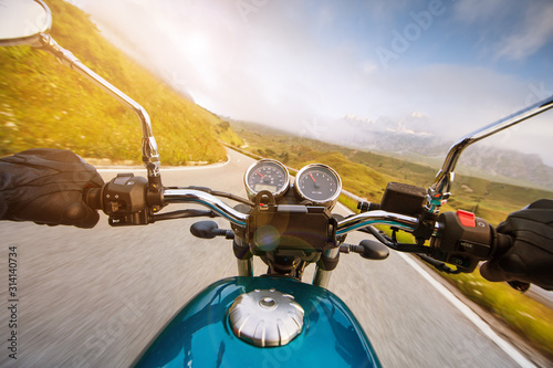 Motorcycle driver riding in Alpine highway, handlebars view, Dolomites, central Europe. photo