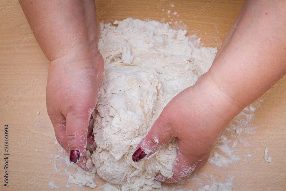 Kneading dough with flour on a wooden table at home Kneading dough with flour on a wooden table at home