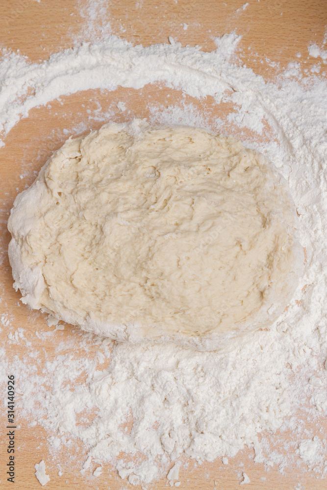 Kneading dough with flour on a wooden table at home Kneading dough with flour on a wooden table at home