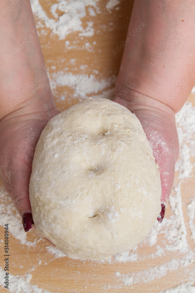 Kneading dough with flour on a wooden table at home Kneading dough with flour on a wooden table at home