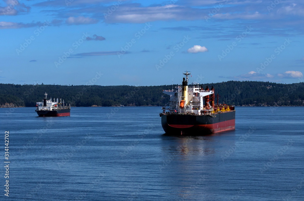 Vancouver harbor, ocean tankers waiting for loading in port white waves in a sunny day on the background scenery of blue sky