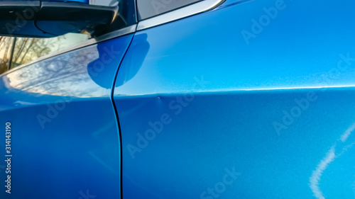 Photography A small dent in the fender of a blue metallic European car