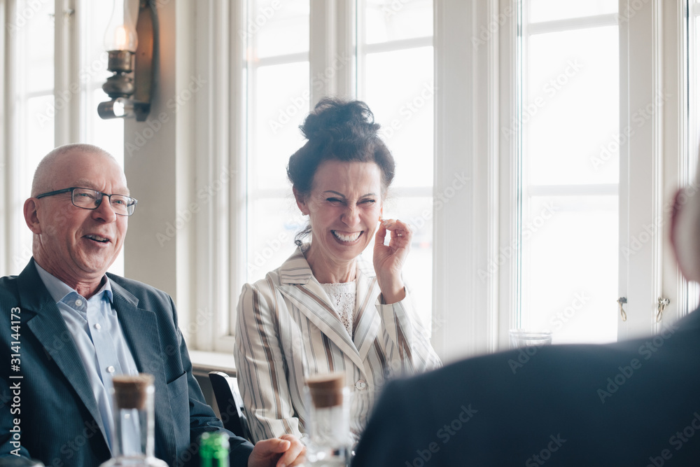 Senior friends smiling while sitting in restaurant Senior friends smiling while sitting in restaurant