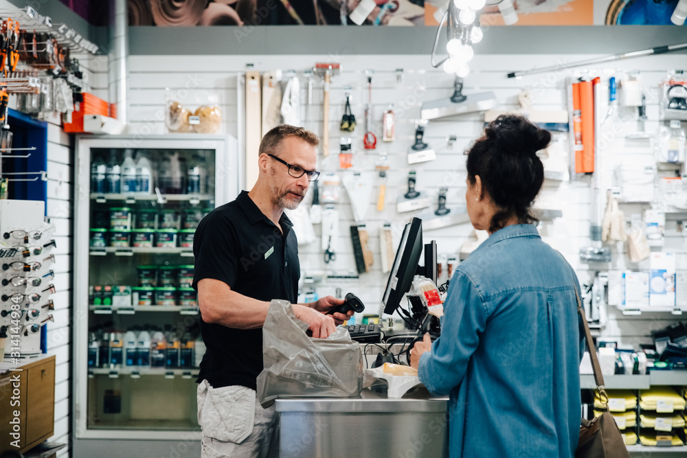 Female Customer talking with shop owner at checkout counter in store Female Customer talking with shop owner at checkout counter in store