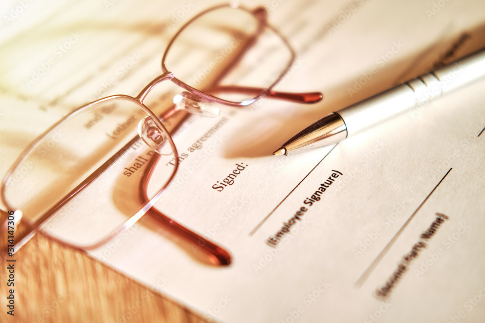 Fototapeta premium Contract sheet with glasses and a pen on a wooden background