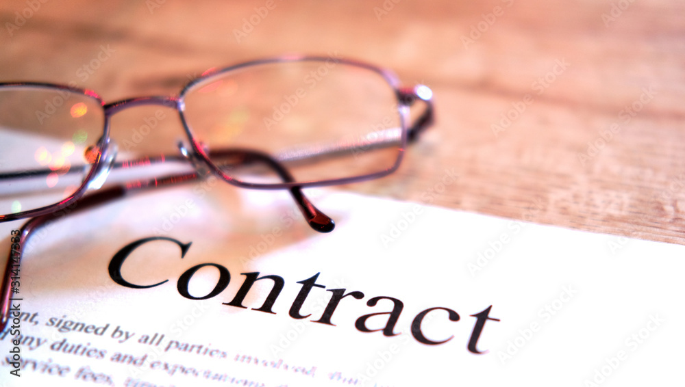 Contract sheet with glasses on a wooden background
