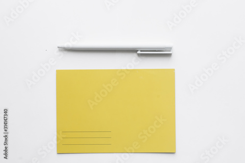 yellow postcard and a pen on white background, write a list