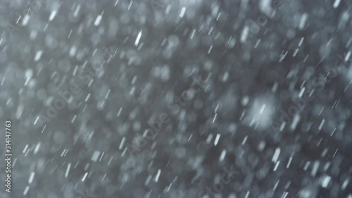 Heavy snow falls and flurries against a dark brown background in slow motion 8K