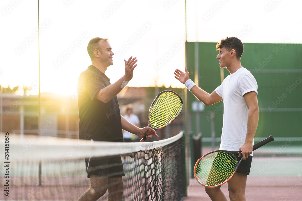 Father and Son Playing Tennis Outdoors. - obrazy, fototapety, plakaty 