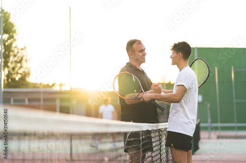Father and Son Playing Tennis Outdoors.