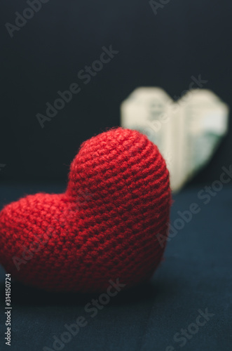 A red heart in the foreground and a paper heart in the background. Romance and love concept