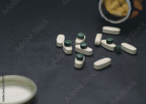White and green pills on a black background