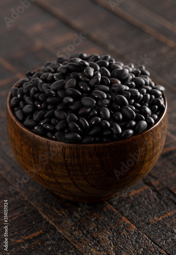 Bowl of Dry Black Beans on a Rustic Wooden Table