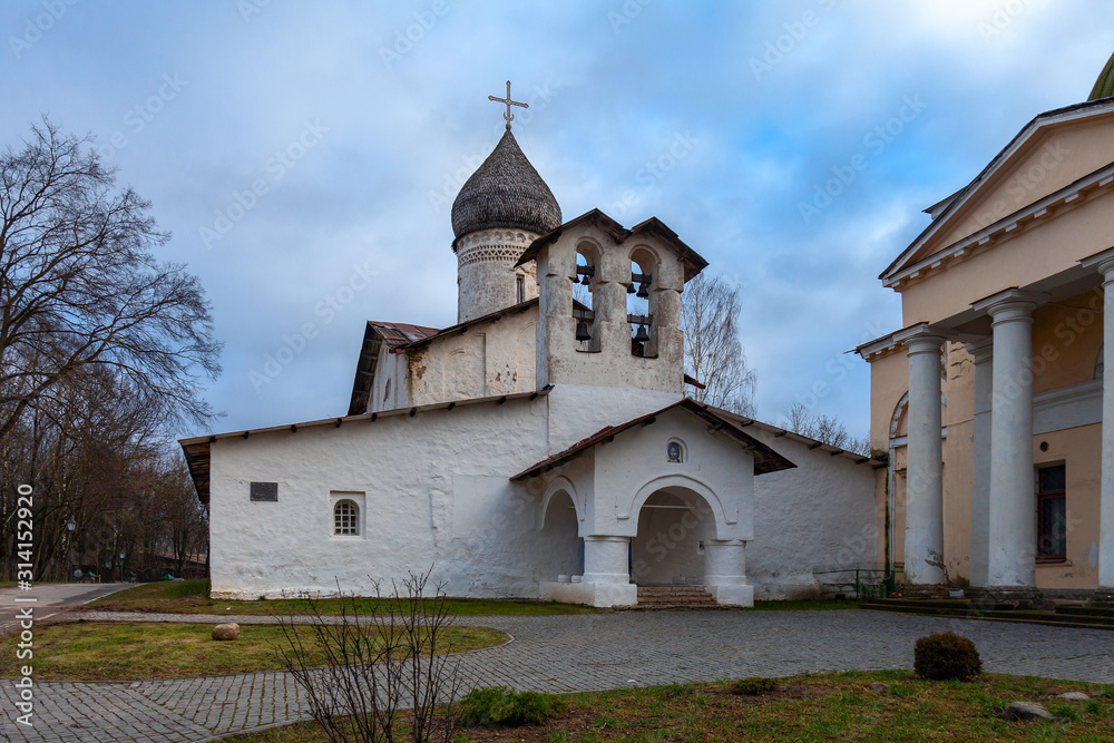 Ancient white-stone Orthodox church with a wooden tiled dome and a double bell tower