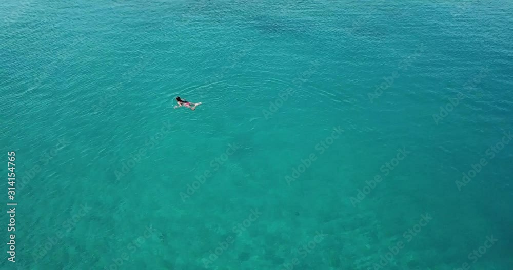 Beautiful young woman swimming in the sea. Aerial view of a girl enjoying summer vacation. Beautiful young woman swimming in the sea. Aerial view of a girl enjoying summer vacation.