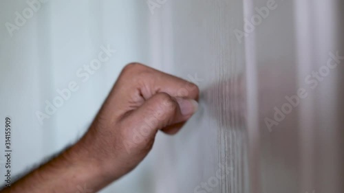Side view hand knocking on wooden door