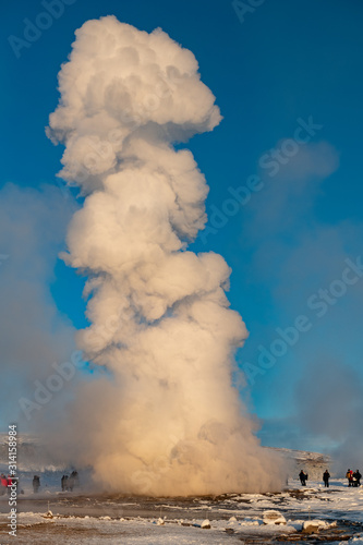 Strokkur geyser erupting in Geysir Geothermal hot spring in Iceland on a clear blue sky day in winter