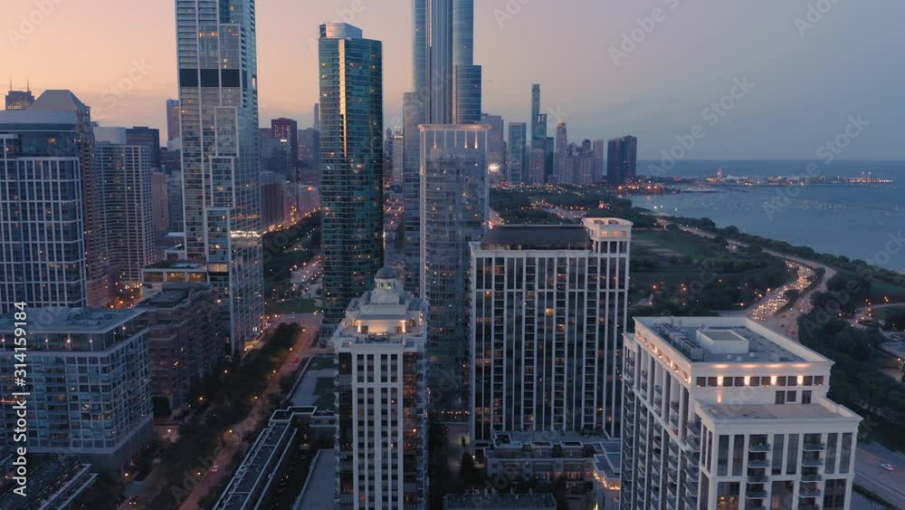 Aerial: Rush hour traffic, train tracks and Chicago skyline at night. USA