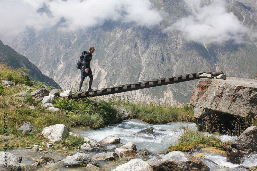 Summer hiking in Cordillera Mountains: hiker crosses the river in the mountains, outdoor adventure concept. Trekking in Cordillera Huayhuash, Peru, South America