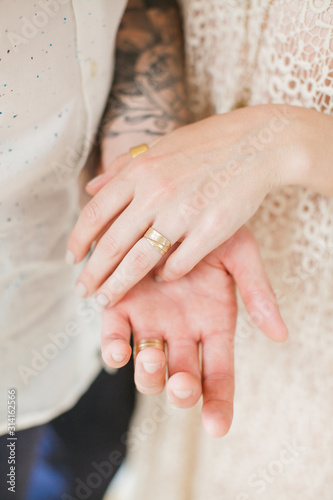 Wedding in boho chic style. Young married couple holding hands with golden rings.
