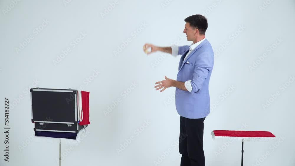 Magician in a suit shows a trick with balls on a white background