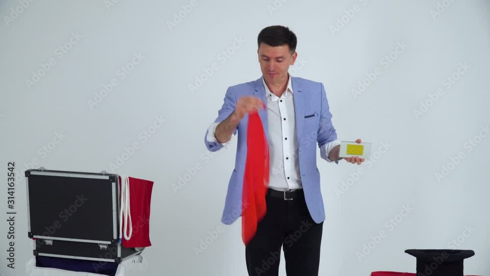 Magician in a suit shows a trick with mirror and shawl on a white background