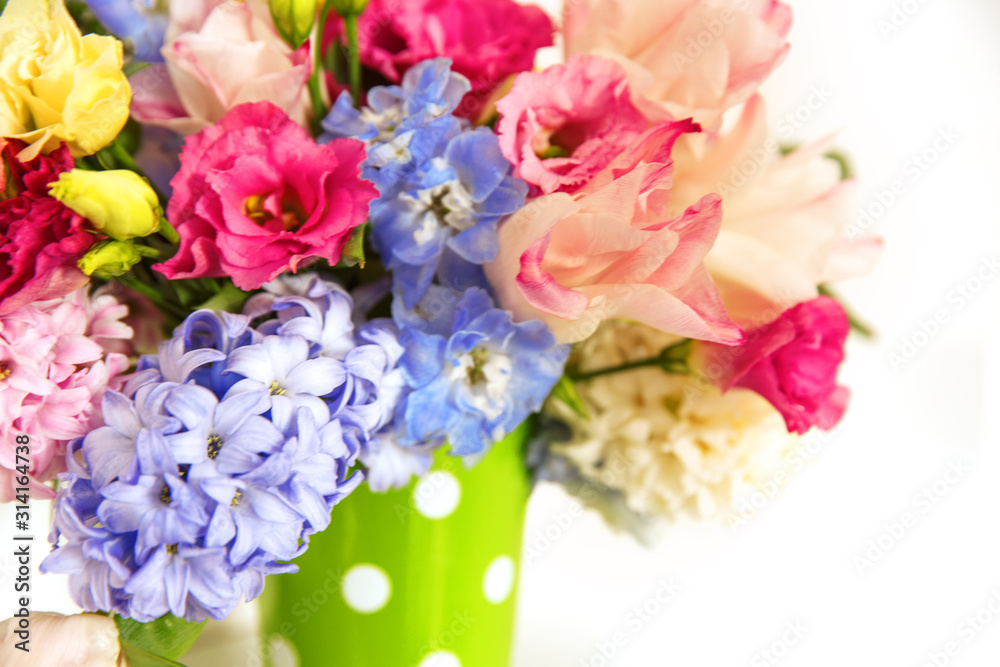 Bouquet of flowers on a shelf by the wall. Flowering branches in a bucket with a pea pattern