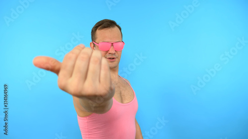 crazy man in pink glasses come here gesture on blue background photo